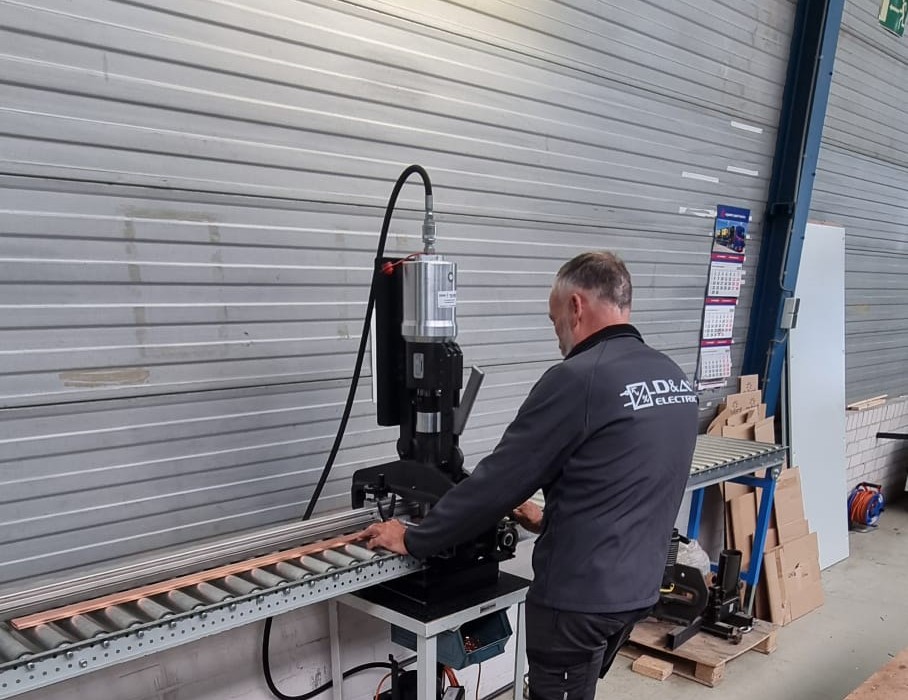 Monteur van D&A Electric bewerkt een koperen rail voor een railsysteem in de werkplaats in Ridderkerk